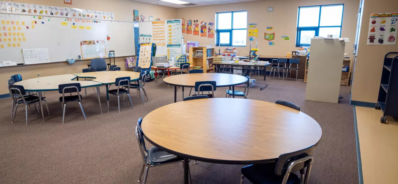 classroom with round tables and board full of student projects