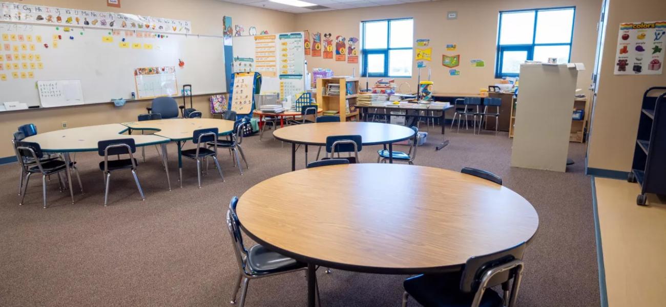classroom with round tables and board full of student projects